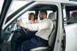 © Viacheslav Yakobchuk - Happy man and woman discussing buying a car in auto salon