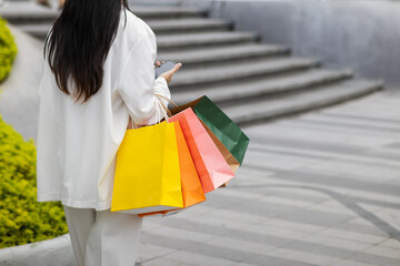 Businesswoman holding shopping paper bags in a shopping mall and is happy after shopping for her needs during the festival. Paper bags containing a lot of products are in hands of Asian businesswoman.