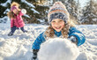 © lmot11 - The girl throws a snowball towards the camera and laughs and has fun. Children play snowballs outside in the snow