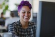 © Fotograf - A woman with vibrant purple hair sits in front of a computer, smiling
