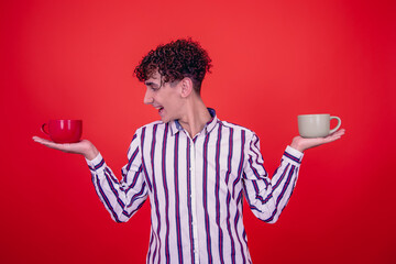 Young attractive guy drinking coffee. Red background.