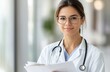 © homeganko - Young doctor smiles while reviewing patient files in a modern clinic during daylight