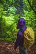 © Michael - Female tourist in hard shell rain jacket looks into a misty jungle from a trail on a rainy day. Poco dos Pulgas Waterfalls, Madeira Island, Portugal, Europe.
