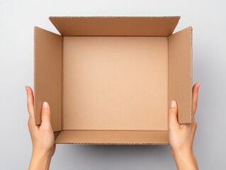 person holding open cardboard box, revealing its empty interior, showcasing simplicity and versatility of packaging. hands emphasize act of unboxing