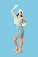 Canvas Print - Happy young woman in winter clothes on blue background