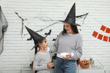 Wall Mural - Little girl with her mother and candies celebrating Halloween at home