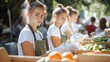 © ifoto - Young people wearing aprons, stood near boxes filled with various food items as they gathered to work together for community service on the sunny day at the park