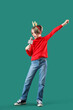 © Pixel-Shot - Cute little boy in Christmas deer horns with microphone singing on green background