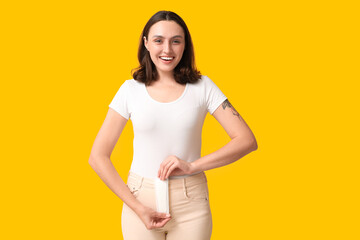 Wall Mural - Beautiful young woman with menstrual pad on yellow background