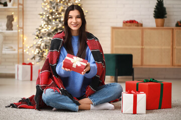 Beautiful young woman with gifts at home on Christmas eve