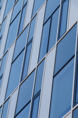 A close-up view of a modern building facade featuring a geometric pattern of blue and white panels with rectangular windows. 