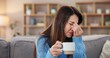 © Nina2024/peopleimages.com - Woman, coffee or headache on sofa in home with brain fog, insomnia or muscle tension. Person, migraine or uncomfortable pressure with stress, temple massage or overwhelmed with burnout in living room