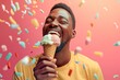 © Lucas - Happy man eating ice cream in a cone with colorful sprinkles falling on him