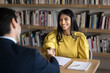 © fizkes - Cheerful Indian student woman talking to male professor in college library, giving handshake to tutor, teacher, thanking for help in study research, sitting at table with bookshelves behind