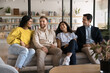 © fizkes - Multiethnic team of cheerful young adult students enjoying work break on couch in professional training center, talking, chatting, smiling, laughing. Casual portrait of diverse office friends