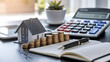 © Rsquare stock - tax day background,House model, house placed on a white surface, next to a calculator, a pencil, and some coins, symbolizing home finances, budgeting, or real estate planning.