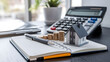 © Rsquare stock - tax day background,House model, house placed on a white surface, next to a calculator, a pencil, and some coins, symbolizing home finances, budgeting, or real estate planning.