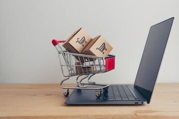 Miniature shopping cart with boxes sits on laptop keyboard, highlighting e commerce