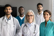 © fizkes - Experienced mature female chief physician head doctor of clinic department pose for group portrait with diverse multicultural staff. Trusted professional medical team with senior leader look at camera