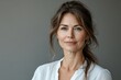 © Nataliia_Trushchenko - Woman with short hair and a white shirt is smiling. She has a light makeup on her face. Portrait of a tender woman in her 50s wearing a classic white shirt in blank studio backdrop