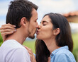 © FotoPush/peopleimages.com - Happy, kissing and couple with love in nature on romantic date for vacation, getaway or weekend trip. Smile, park and man and woman with connection, care and bonding outdoor in garden on holiday.