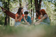 © qunica.com - Group of friends sitting together in a sunny park, sharing a relaxed moment and enjoying the outdoors.