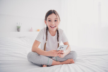 Sticker - Portrait of cheerful adorable nice girl enjoying weekend sitting bed apartment white light room interior indoors