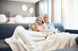 © CamPen2000/peopleimages.com - Blanket, coffee and mature couple on sofa in living room of home together for bonding, break or romance. Cozy, cuddle or hug with happy man and woman in apartment for love, relationship or drink