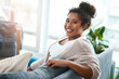© Sanc/peopleimages.com - Girl, portrait and happy on sofa for relax, comfort and positivity in home living room. Woman, student and smile on couch for study break, stress free and optimistic on weekend in Brazil apartment