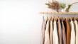 © weerasak - Stylish clothing displayed on hangers with decorative plants on a minimalist background.