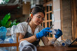 © Odua Images - asian woman wearing gloves holding cutter for crafting plastic bottle