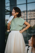 © qunica.com - A confident woman in a striped shirt holds papers while attending an outdoor meeting. She appears engaged and attentive, showcasing professionalism and communication skills.
