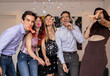 © PintoArt - Group of friends having fun blowing party blowers celebrating new year's eve