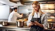 © Abele - young blonde woman using cellphone while working in restaurant kitchen