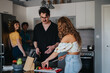 © qunica.com - A group of friends enjoying time together while preparing a meal in a contemporary kitchen. They are smiling and having fun, showcasing a relaxed and joyful atmosphere.
