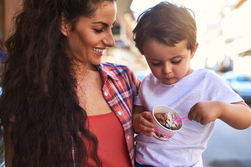 Happy mother, kid and eating ice cream in city for dessert, sugar and food in summer. Mom, child and smile with gelato outdoor for hungry boy with snack, sweets and love of family bonding together