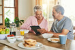 © TamJam/peopleimages.com - Smile, breakfast and senior couple with tablet for reading morning news, internet puzzle or story. Happy man, woman or technology in retirement home for article, online information or relax with food