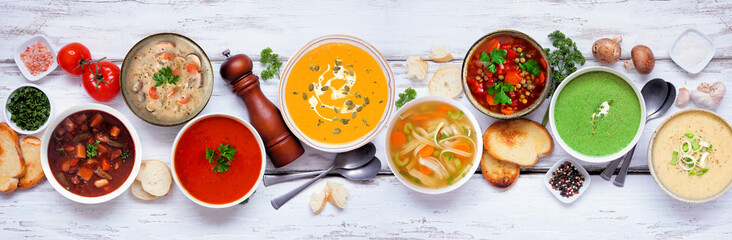 Wall Mural - Variety of delicious homemade soups. Above view table scene on a white wood banner background. Warm and cozy food concept.