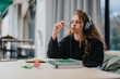 © qunica.com - A high school student sits at a desk, wearing headphones and thoughtfully chewing a pencil while looking away, suggesting concentration and contemplation during study time.