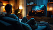 © altitudevisual - Person sitting on a couch watching a large television displaying a cityscape at night. The cozy living room features warm lighting, wooden furniture, and modern decor.