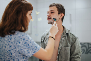 Poster - A couple getting ready for a night out, with the woman helping the man shave in the bathroom. Captures a moment of intimacy and preparation.