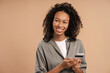 © Maria Vitkovska - Smiling African American woman holding mobile phone looking to the side in studio