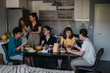 © qunica.com - A group of friends enjoying a relaxed meal in a modern kitchen, sharing food and laughter around a table. The atmosphere is warm and inviting.