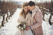 © TiA - Bride and groom embracing in snowy vineyard during winter wedding