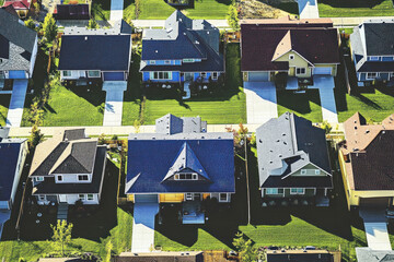 Large group of houses with solar panels on roofs, clear blue sky background, hint of trees in the distance.