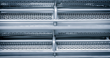 Aufkleber - The image is of a metal structure with a lot of holes in it. The holes are arranged in a grid pattern, and the structure appears to be made of metal. Scene is industrial and utilitarian