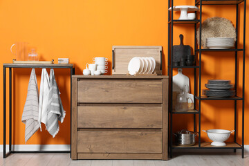 Wall Mural - Storage stands and chest of drawers with kitchenware near orange wall indoors