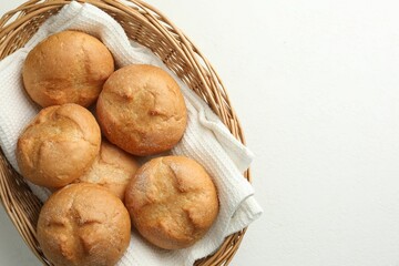 Canvas Print - Wicker basket with homemade tasty buns on white table, top view. Space for text