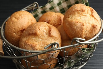 Wall Mural - Metal basket with homemade tasty buns on black wooden table, closeup