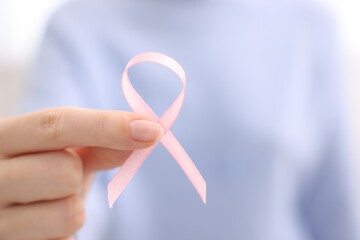 Wall Mural - Woman with pink ribbon on light background, closeup with space for text. Breast cancer awareness